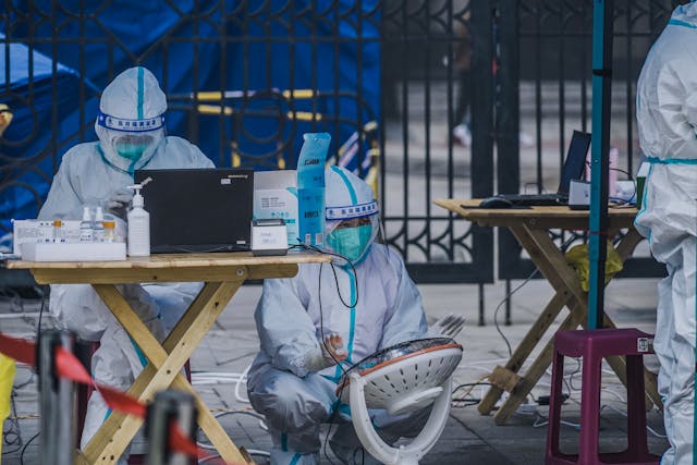 Medical staff in protective gear entering an isolation ward